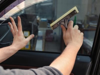 Worker applying tinting foil onto car window